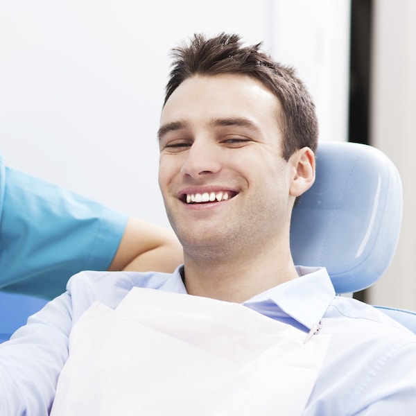 Young man sitting in a blue dental treatment chair about to get restorative dentistry