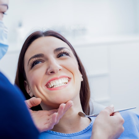 A close up of a woman in a dental chair smiling while getting family dentistry