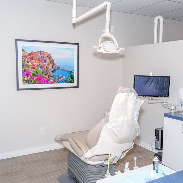 A dental treatment room in our office featuring a dental chair, TV, and a colorful painting 