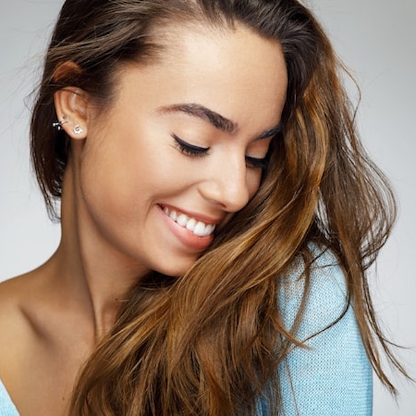 A woman with long brown hair looking down smiling